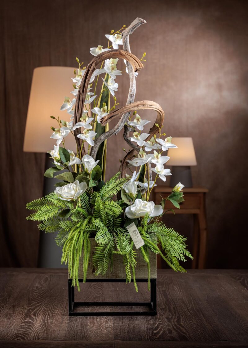 Composizione di fiori artificiali finti con orchidea e rami contorti