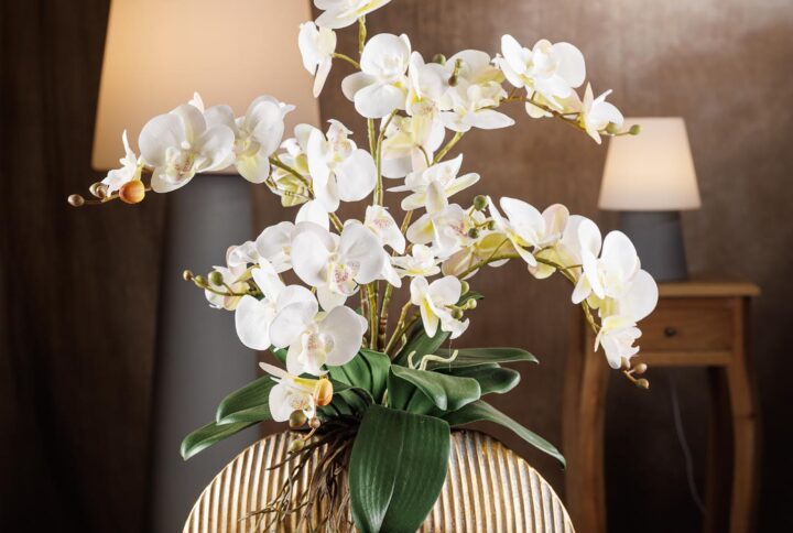 Composizione di fiori artificiali finti con orchidea e vaso dorato